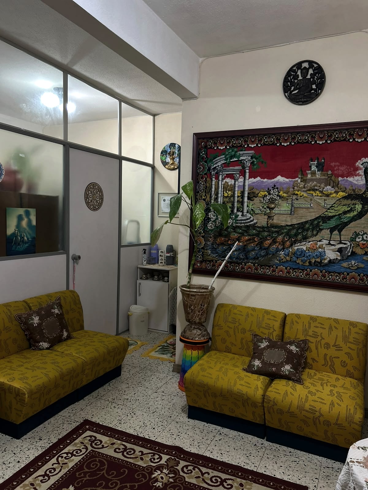 Sala de convivência com sofás e tapeçaria decorativa.