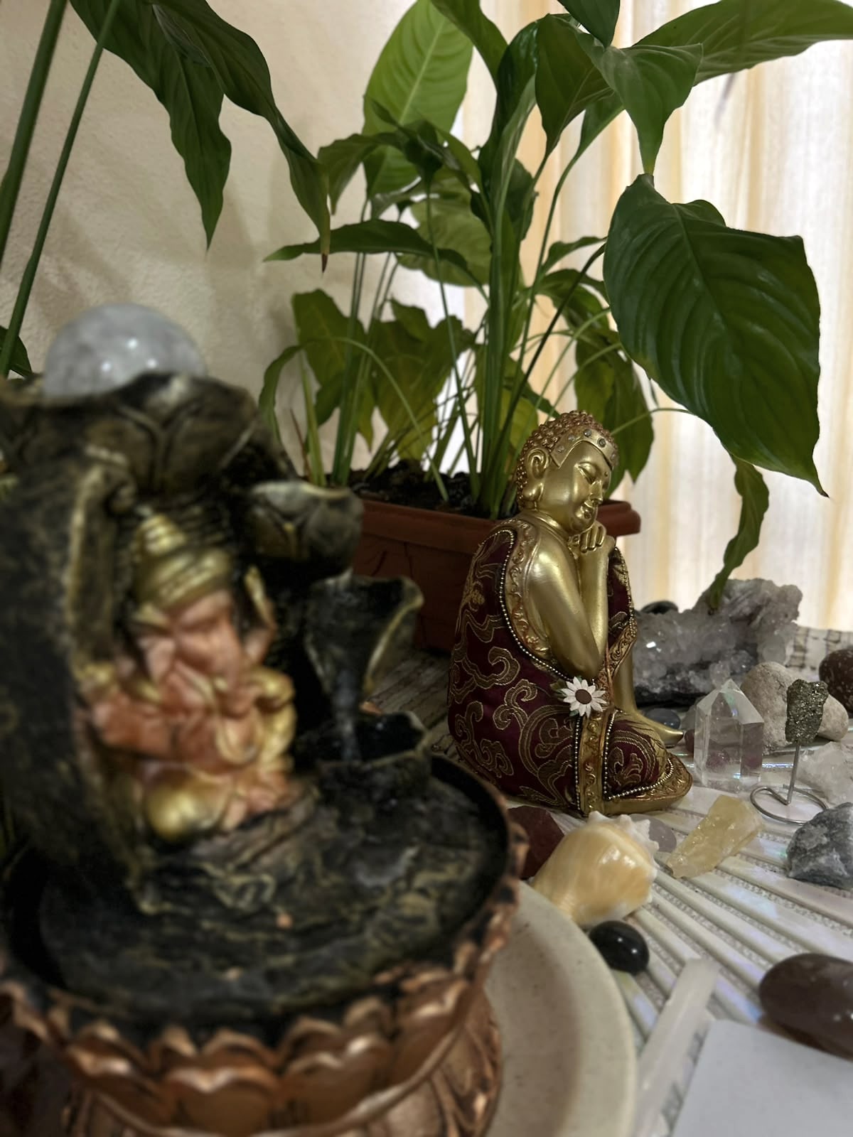 Peça decorativa dourada entre cristais e plantas.